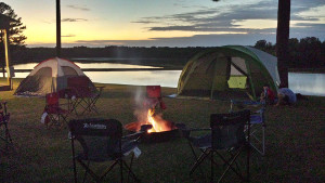 Serene sunset over a lake with tents set up by cub scouts.